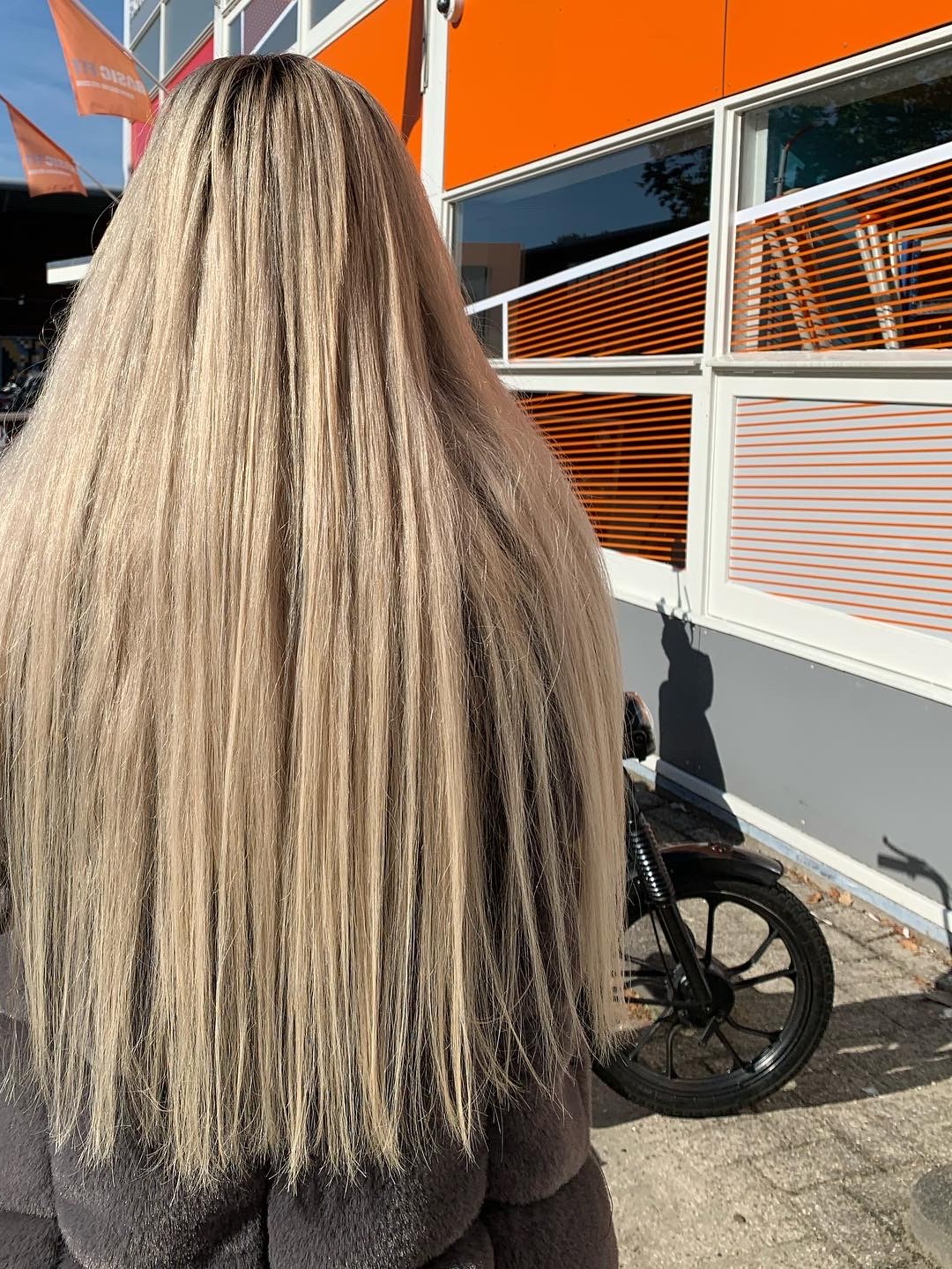 Lang, steil blond haar met lichtere lengtes, van achteren gezien buiten