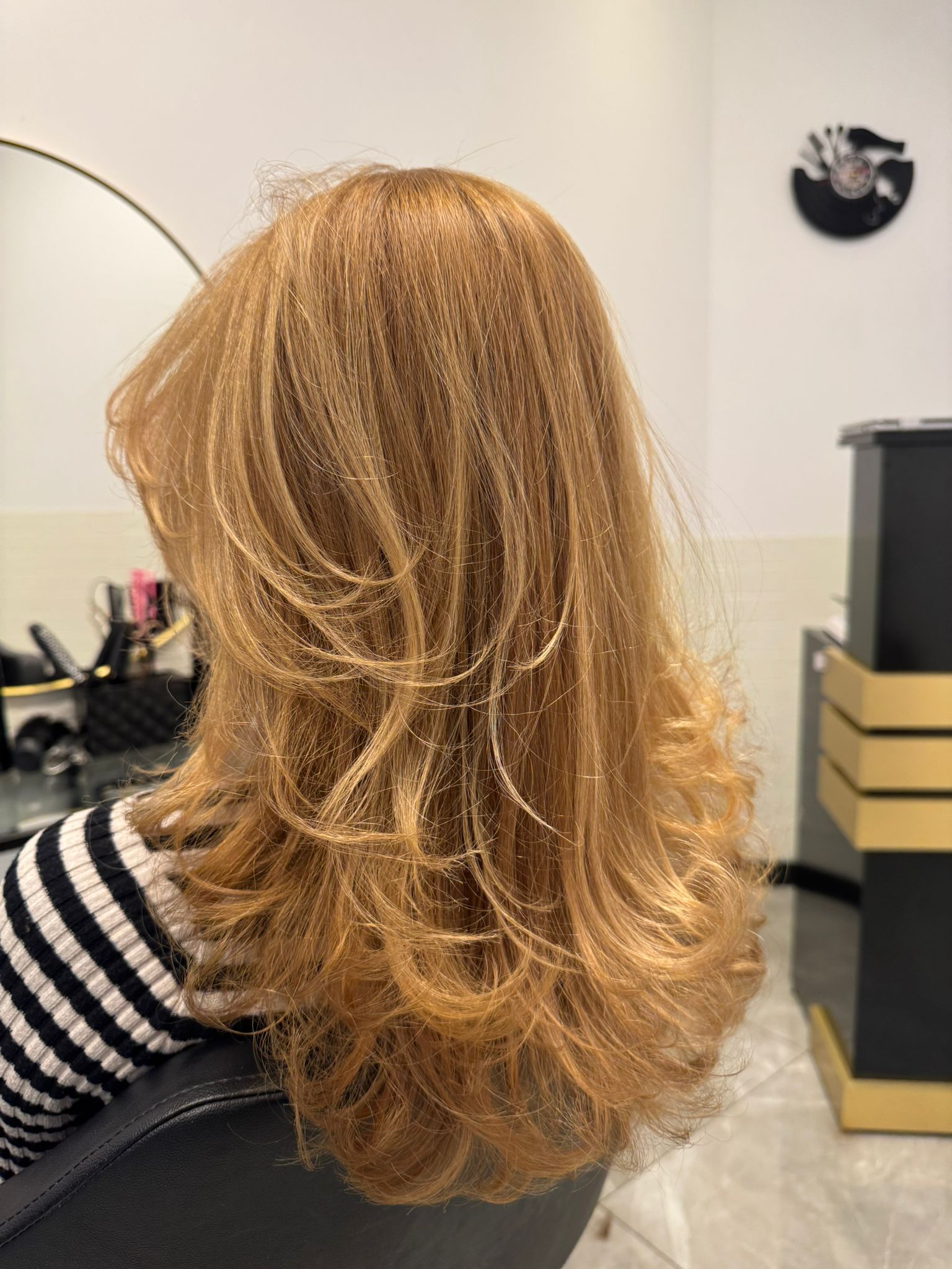 Koperblond haar in laagjes, van achteren gezien in de salon