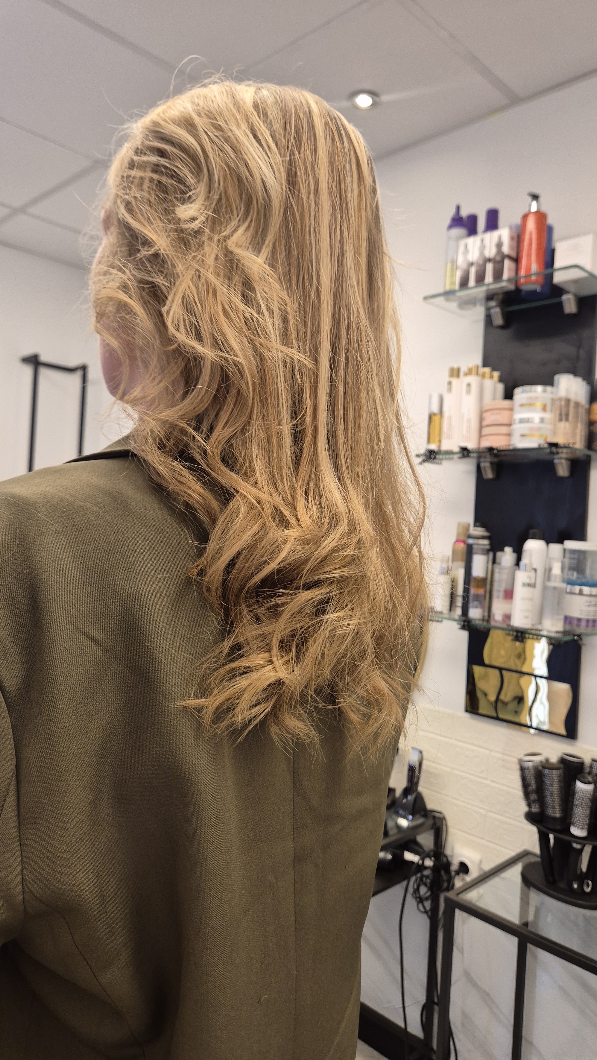 Blond haar in losse golven, van opzij gezien in de salon